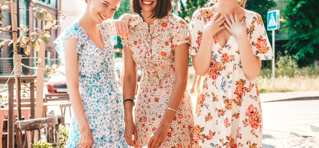 Three young beautiful smiling hipster girls in trendy summer sundress.Sexy carefree women posing on the street background.Models having fun and hugging.Discussing and walking after shopping